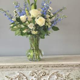 White roses and blue delphinium in a clear glass vase