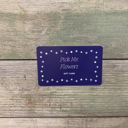 Purple Pick Me Flowers gift card on a wood surface