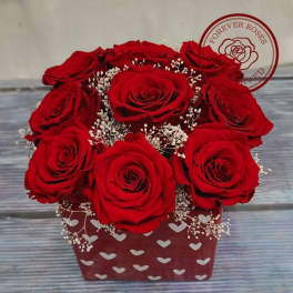 Red roses arranged in a heart-patterned box with baby's breath