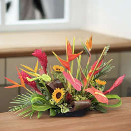 Tropical flower arrangement with orange heliconia and yellow sunflowers in a low container