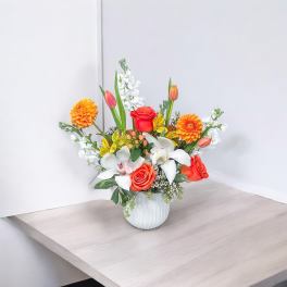 Mixed bouquet in a white vase with orange, red, and white flowers