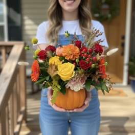 Pumpkin vase arrangement with roses, dahlias, and autumn accents