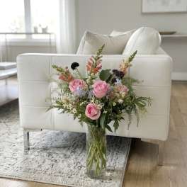 Pink roses and mixed flowers arranged in a clear glass vase