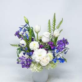 White and purple floral arrangement in a white vase