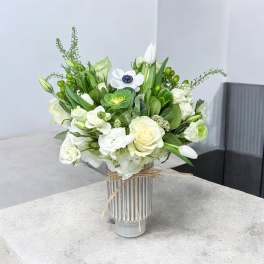 White and green floral arrangement in a striped glass vase
