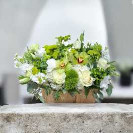 White and green floral arrangement in a wooden box