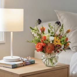 Mixed bouquet in a clear glass vase on a bedside table