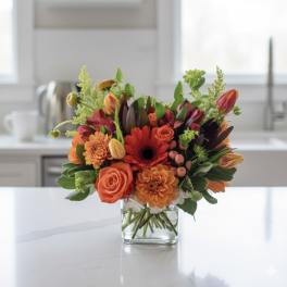 Orange and red mixed bouquet in a clear glass vase