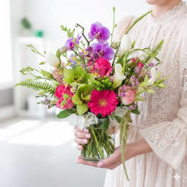 Woman holding a colorful bouquet in a clear glass vase