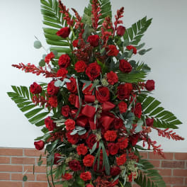 Tall red rose and carnation standing spray with palm leaves on a metal easel