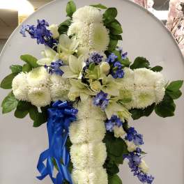 White floral cross arrangement with blue ribbon on an easel