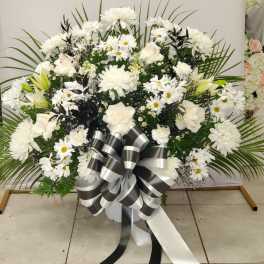 Large white floral spray with daisies, roses, and a black-and-white ribbon bow