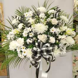 White funeral spray with daisies and chrysanthemums on a stand