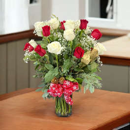 Red and white roses in a glass vase with a red ribbon