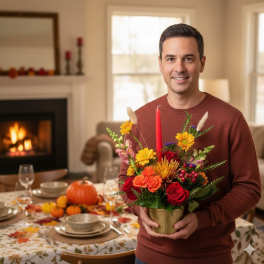 Man holding a fall floral arrangement in a gold vase