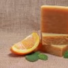 Stacked orange soap bars with an orange slice and mint leaves