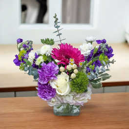 Mixed bouquet in a square glass vase with purple, white, and pink flowers