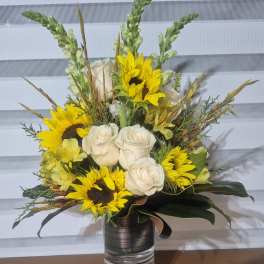 Bouquet of white roses and yellow sunflowers in a glass vase