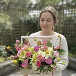 Woman holding a wooden box arrangement of pink and white flowers