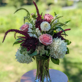 Pink roses and white blooms arranged in a clear glass vase