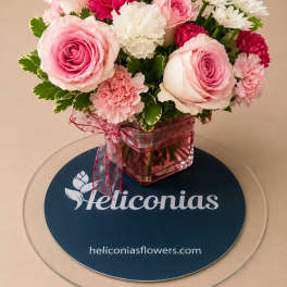 Pink roses and carnations arranged in a square glass vase