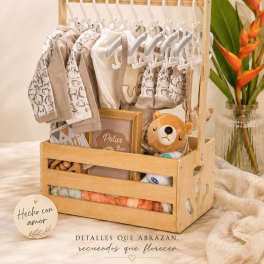 Baby gift basket with clothes, a plush bear, and a wooden frame
