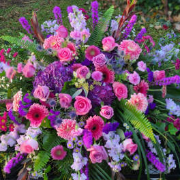 Large pink and purple floral arrangement with roses and mixed blooms