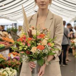 Woman holding a mixed bouquet in a ribbed metal vase