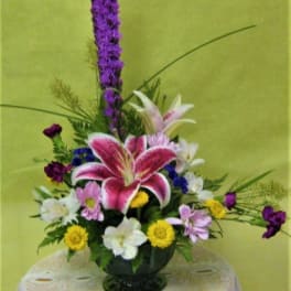 Mixed floral arrangement with pink lilies and purple flowers in a vase