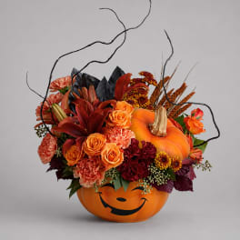 Halloween pumpkin container filled with orange and red flowers