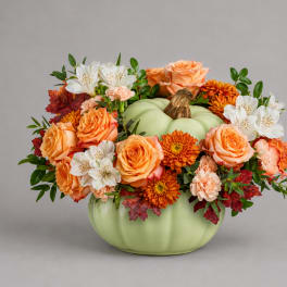 Orange and white flowers arranged in a pumpkin-shaped vase