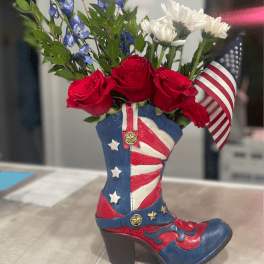 Red roses and white daisies arranged in a patriotic cowboy boot vase
