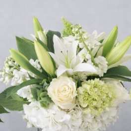 White lilies and roses arranged in a clear glass vase