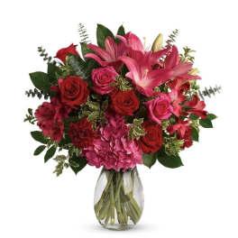 Bouquet of pink lilies and red roses in a clear glass vase