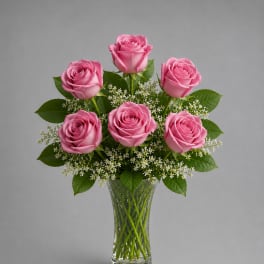 Pink roses arranged in a clear glass vase with small white filler flowers