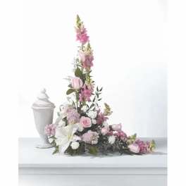 Tall pink and white floral arrangement beside a white urn
