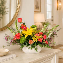 Colorful mixed flower arrangement in a white vase on a table