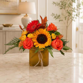 Sunflower and rose arrangement in a square amber vase