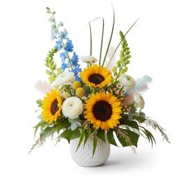 Sunflowers and white ranunculus in a white vase with blue delphinium