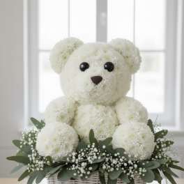 White teddy bear made of flowers in a wicker basket with greenery