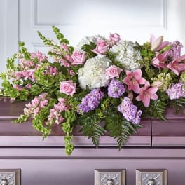 Pink lilies and roses arranged with white hydrangeas on a casket