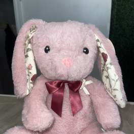 Pink plush bunny with floral-patterned ears and feet, wearing a burgundy bow