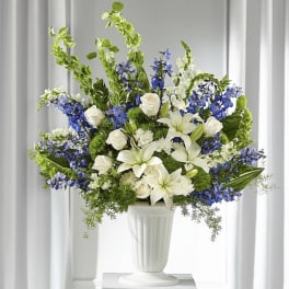 White lilies and roses with blue flowers in a white vase