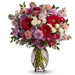 Mixed pink and purple bouquet with red gerbera daisies in a glass vase