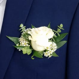 White rose boutonniere with small white filler flowers on a navy jacket