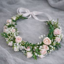 Floral crown with pale pink roses and white filler flowers tied with a ribbon