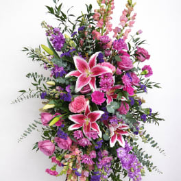 Tall standing floral spray with pink lilies and roses in pink and purple tones