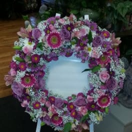 Heart-shaped floral wreath on a standing easel with pink and purple flowers