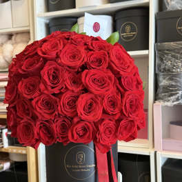 Large bouquet of red roses in a black hat box with a red ribbon
