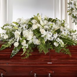 White floral casket spray with lilies, roses, and daisies